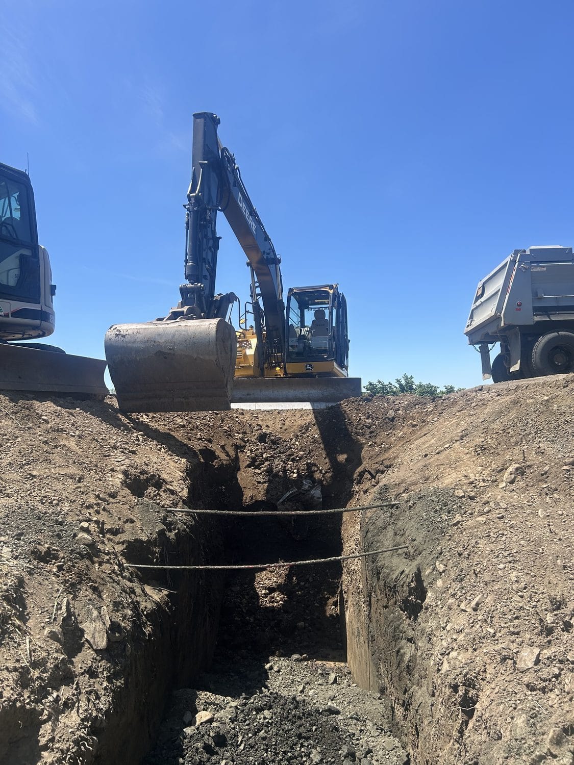 Deep trench cut with the truck alongside for spoil.