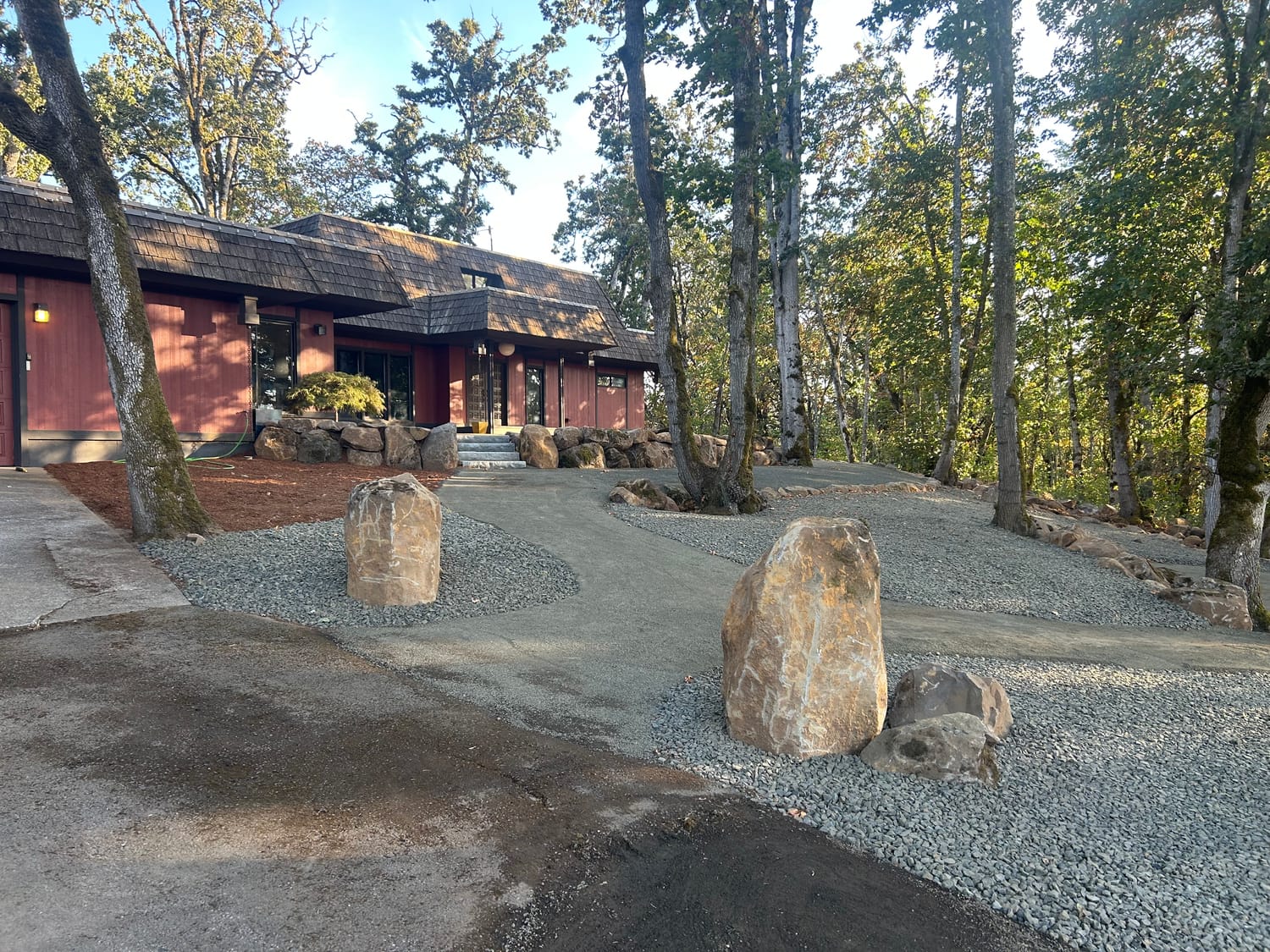 Standing boulders set at the driveway with a rock wall along the house.